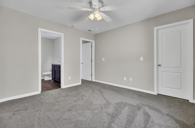 unfurnished bedroom with ensuite bath, ceiling fan, and dark carpet