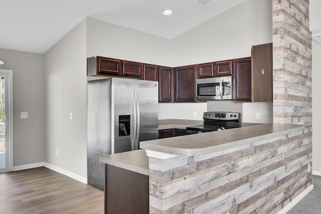 kitchen featuring stainless steel appliances, light wood-type flooring, kitchen peninsula, dark brown cabinetry, and lofted ceiling