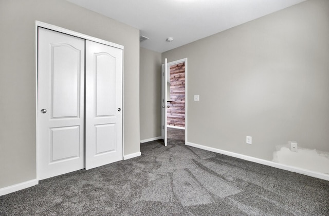 unfurnished bedroom with dark colored carpet and a closet