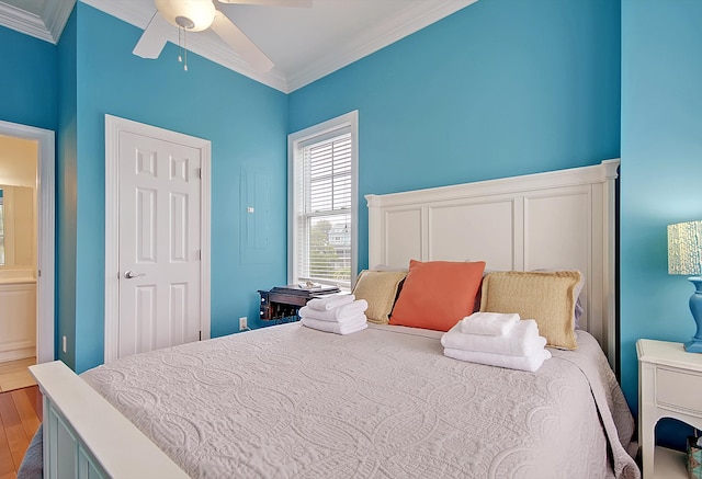 bedroom featuring connected bathroom, wood-type flooring, ceiling fan, and crown molding