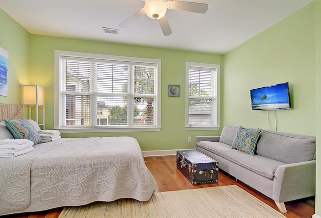 bedroom featuring wood-type flooring, multiple windows, and ceiling fan