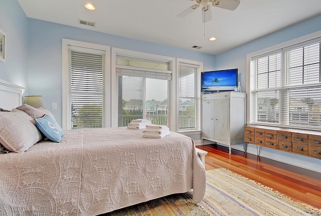 bedroom featuring multiple windows, hardwood / wood-style flooring, and ceiling fan