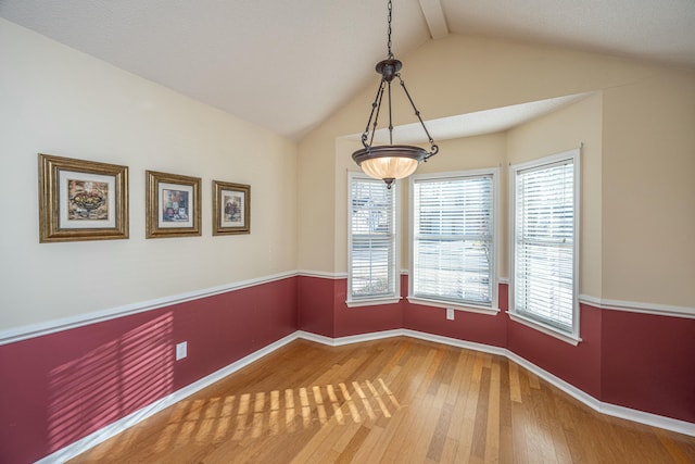 empty room featuring hardwood / wood-style flooring, lofted ceiling, and a wealth of natural light