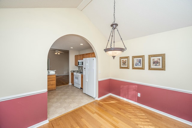 unfurnished dining area with ceiling fan, lofted ceiling, and light wood-type flooring