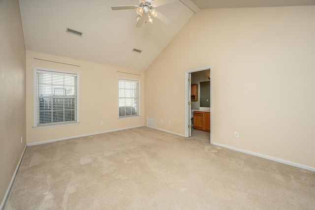 carpeted spare room featuring ceiling fan and high vaulted ceiling