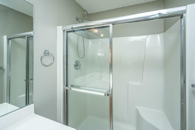 bathroom with walk in shower, vanity, and a textured ceiling