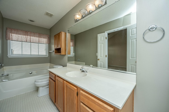 bathroom featuring tile patterned floors, a tub to relax in, toilet, a textured ceiling, and vanity