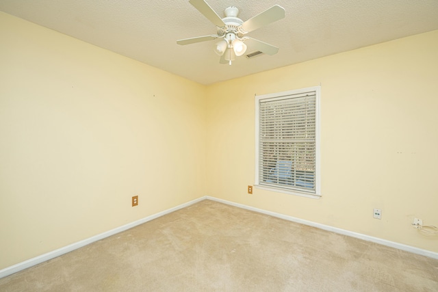 unfurnished room featuring ceiling fan, light carpet, and a textured ceiling