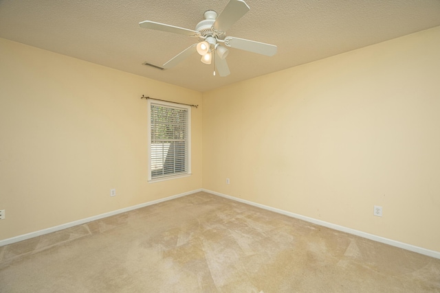 empty room with ceiling fan, light colored carpet, and a textured ceiling