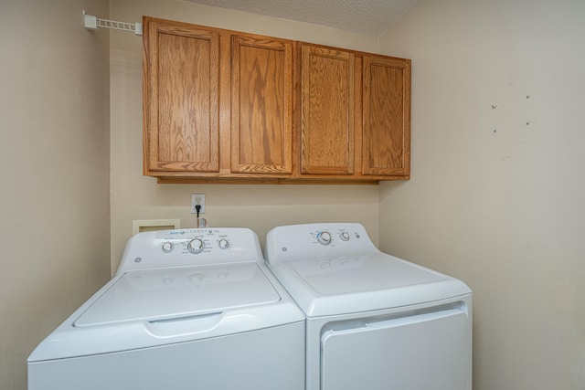 clothes washing area featuring a textured ceiling, cabinets, and washing machine and clothes dryer