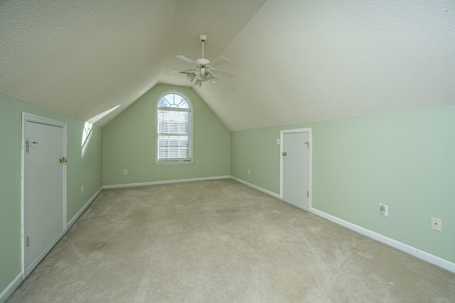 additional living space featuring ceiling fan, light colored carpet, lofted ceiling, and a textured ceiling