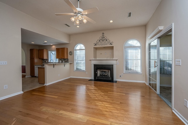 unfurnished living room featuring sink, light hardwood / wood-style floors, and ceiling fan