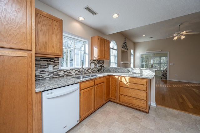 kitchen with backsplash, light stone countertops, kitchen peninsula, and dishwasher