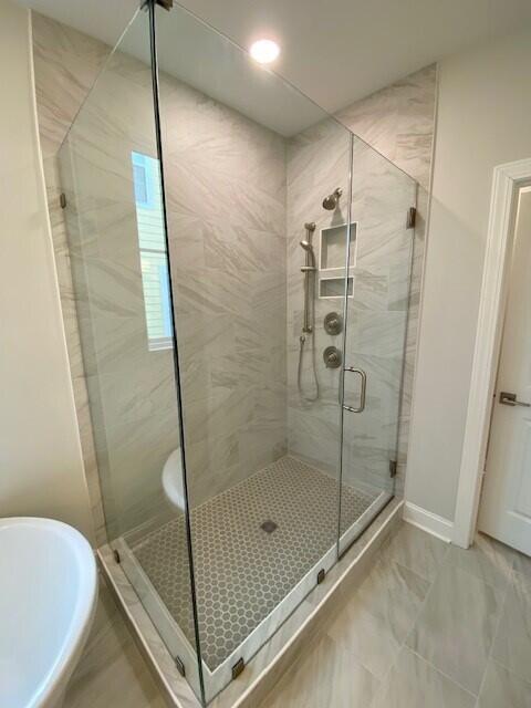 bathroom featuring a stall shower, a soaking tub, and baseboards