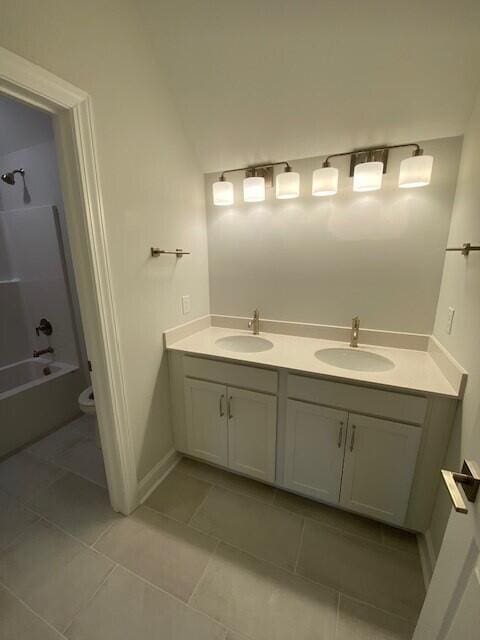 bathroom featuring toilet, double vanity, a sink, and shower / bathtub combination