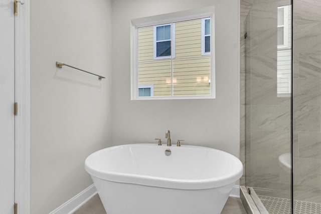 bathroom with a freestanding tub, a shower stall, and baseboards