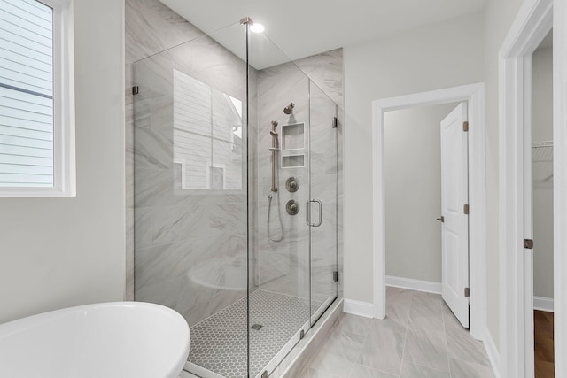 full bath with a stall shower, a soaking tub, marble finish floor, and baseboards