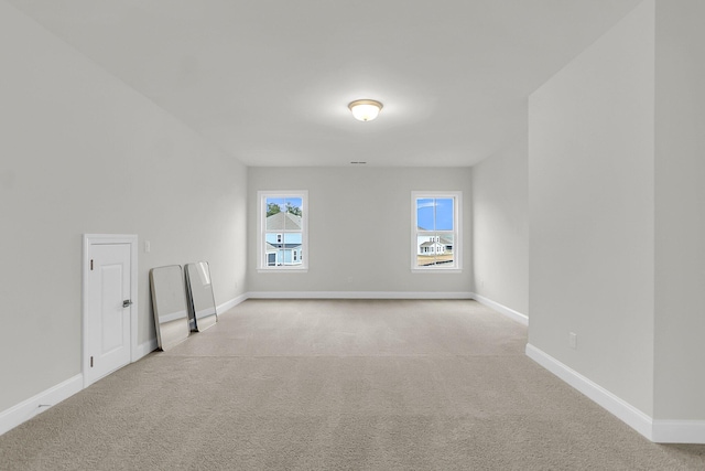 additional living space with baseboards and light colored carpet