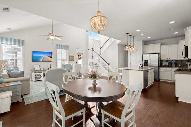 dining area featuring ceiling fan with notable chandelier, high vaulted ceiling, dark wood-type flooring, and sink