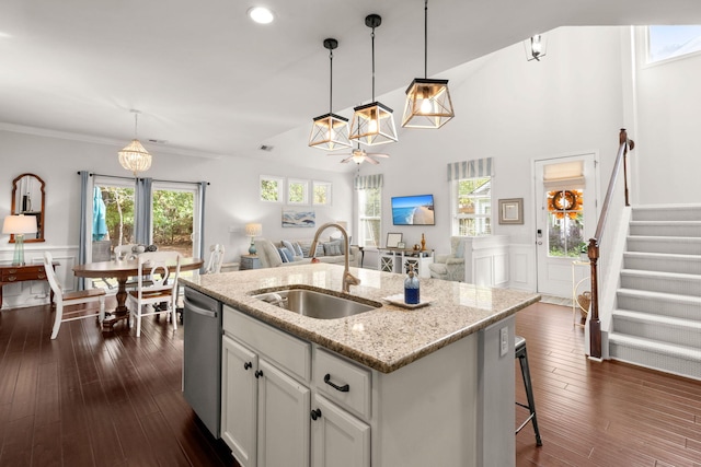 kitchen featuring dishwasher, a kitchen island with sink, sink, light stone counters, and white cabinetry