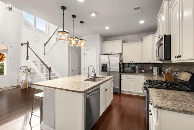 kitchen featuring white cabinetry, sink, stainless steel appliances, dark hardwood / wood-style floors, and an island with sink