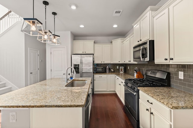 kitchen with appliances with stainless steel finishes, an island with sink, dark hardwood / wood-style floors, and sink