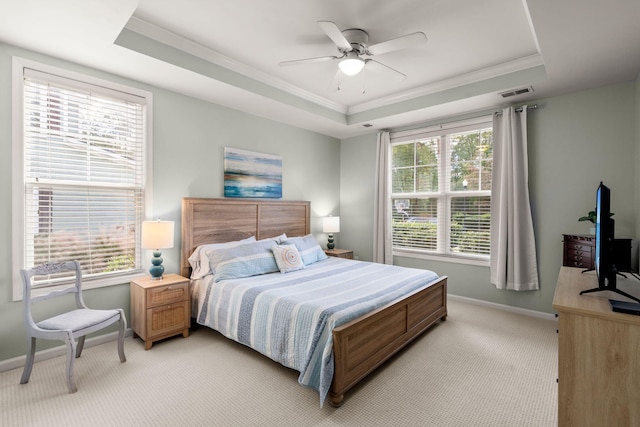 carpeted bedroom featuring a tray ceiling, multiple windows, crown molding, and ceiling fan