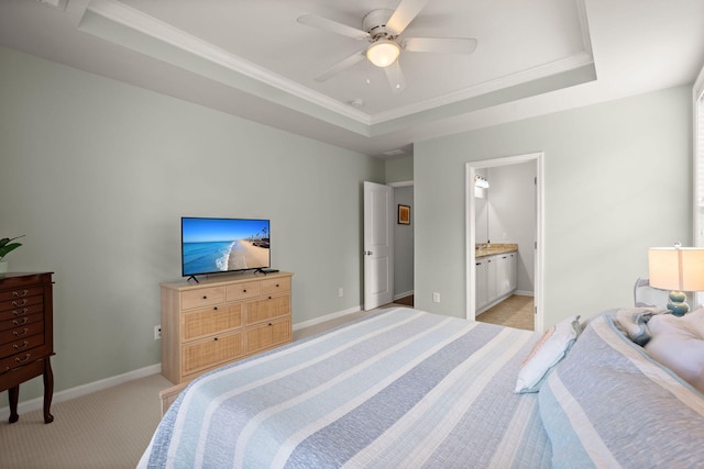 bedroom featuring a raised ceiling, ensuite bath, ceiling fan, and light carpet