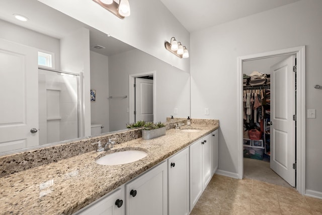 bathroom featuring tile patterned floors, vanity, toilet, and a shower with door