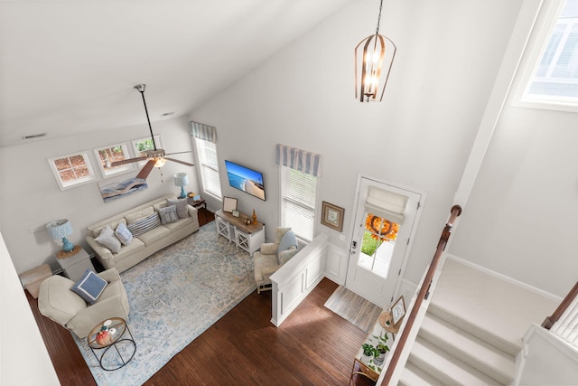 living room featuring dark hardwood / wood-style floors, ceiling fan with notable chandelier, and high vaulted ceiling