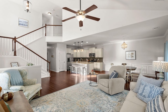 living room with ornamental molding, ceiling fan, dark wood-type flooring, sink, and high vaulted ceiling