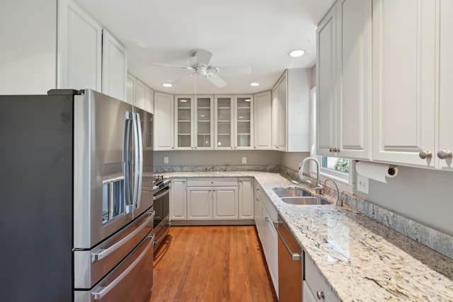 kitchen with stainless steel appliances, white cabinets, a sink, and light wood-style flooring