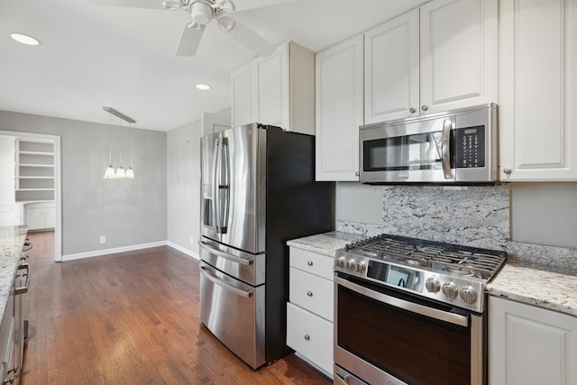 kitchen featuring baseboards, dark wood finished floors, light stone counters, appliances with stainless steel finishes, and white cabinetry