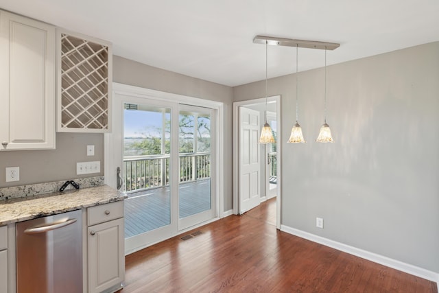 kitchen featuring baseboards, visible vents, dark wood-style floors, light stone counters, and hanging light fixtures