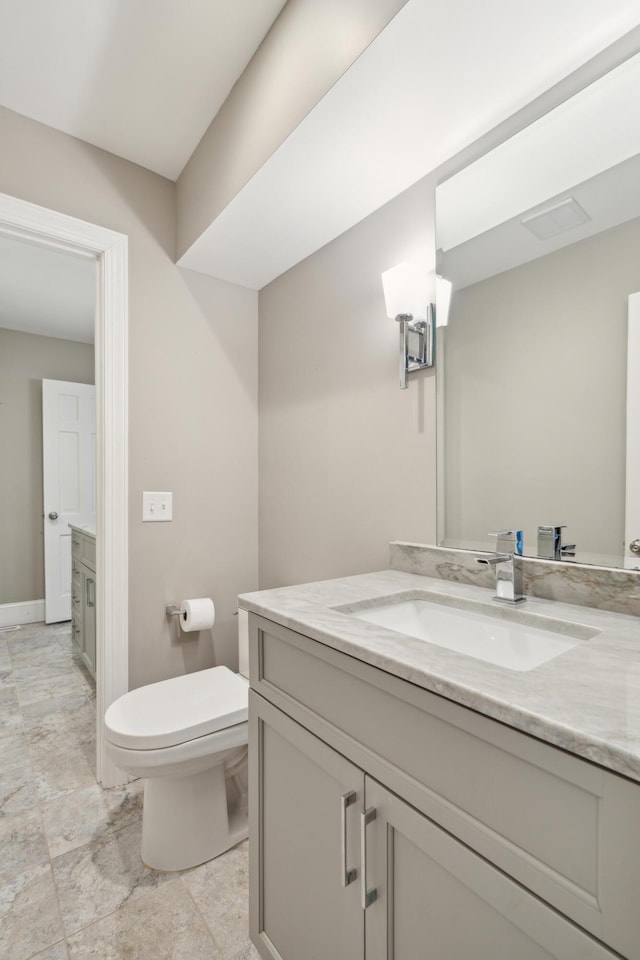 bathroom with baseboards, vanity, and toilet