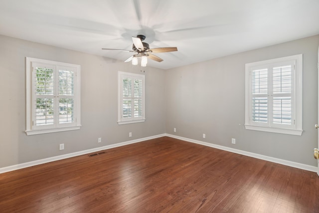 empty room with plenty of natural light, dark wood finished floors, visible vents, and baseboards