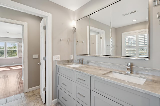 full bathroom featuring visible vents, a sink, baseboards, and double vanity