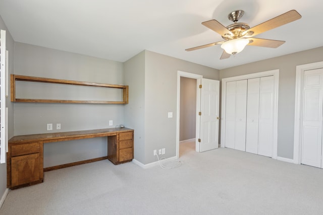 unfurnished office featuring a ceiling fan, baseboards, carpet flooring, and built in study area