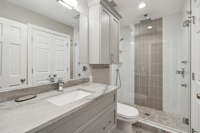 bathroom with visible vents, toilet, a shower stall, and vanity