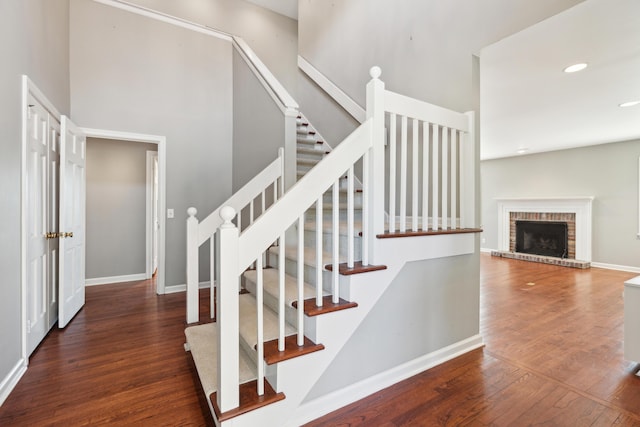 stairs featuring a brick fireplace, wood-type flooring, baseboards, and recessed lighting