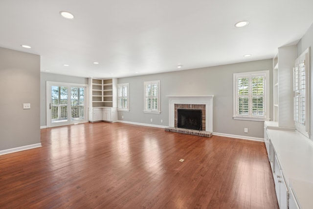 unfurnished living room with a fireplace, baseboards, wood finished floors, and recessed lighting