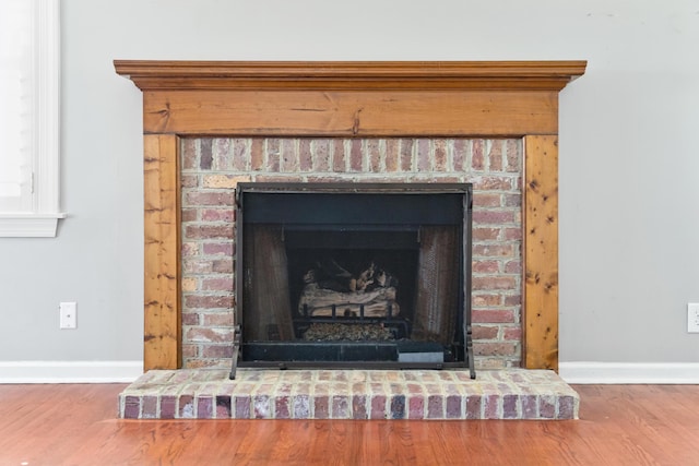 details with a brick fireplace, baseboards, and wood finished floors