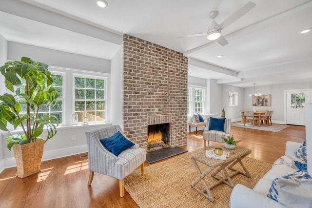 living room with brick wall, ceiling fan, light wood-type flooring, and a brick fireplace