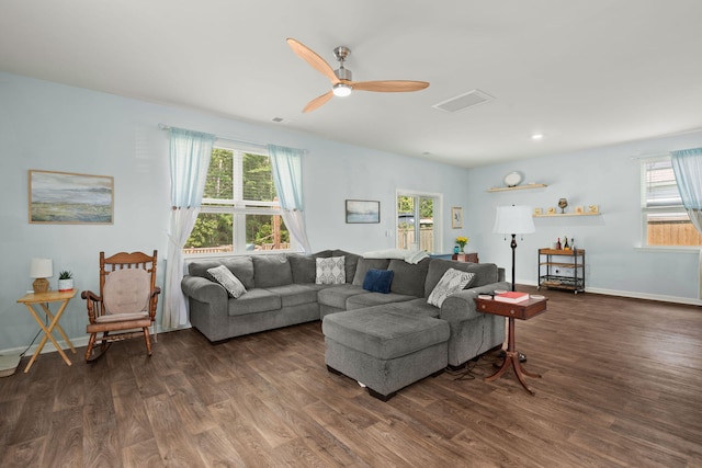 living room featuring baseboards, dark wood-type flooring, a healthy amount of sunlight, and ceiling fan