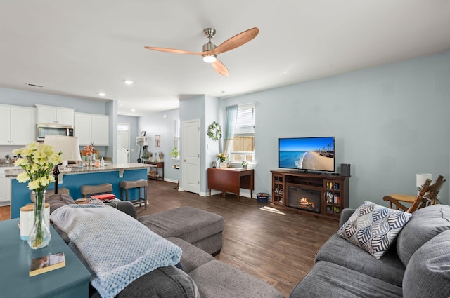 living area with recessed lighting, dark wood-type flooring, and ceiling fan