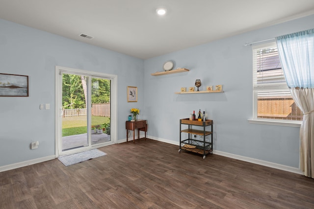 unfurnished room with dark wood finished floors, baseboards, visible vents, and a wealth of natural light