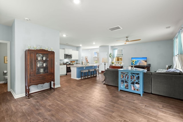 living room featuring a healthy amount of sunlight, visible vents, dark wood-style flooring, and ceiling fan