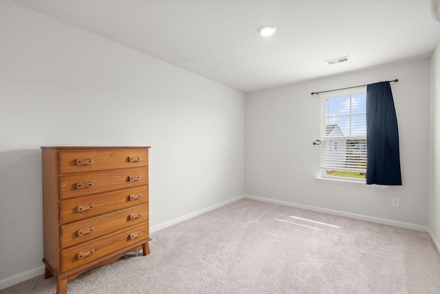 spare room with visible vents, light colored carpet, and baseboards