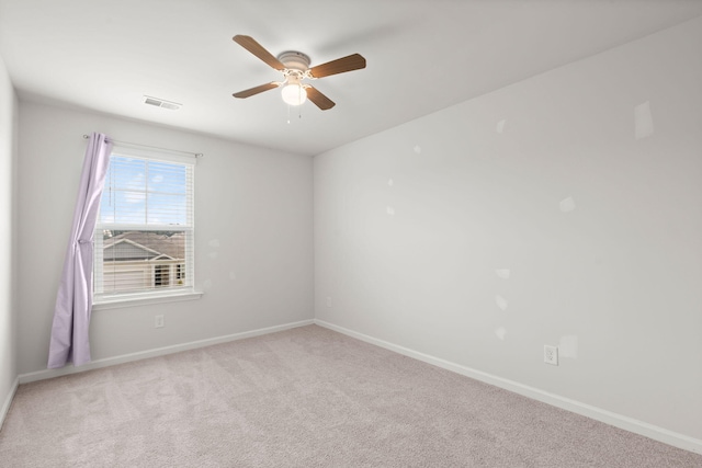 carpeted spare room with visible vents, baseboards, and a ceiling fan