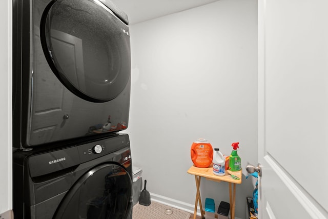 washroom with laundry area, baseboards, and stacked washing maching and dryer